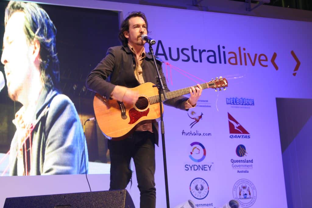 Musician performing with acoustic guitar.