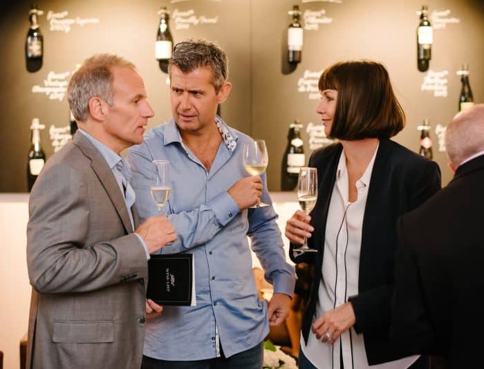 Three people enjoying wine conversation.
