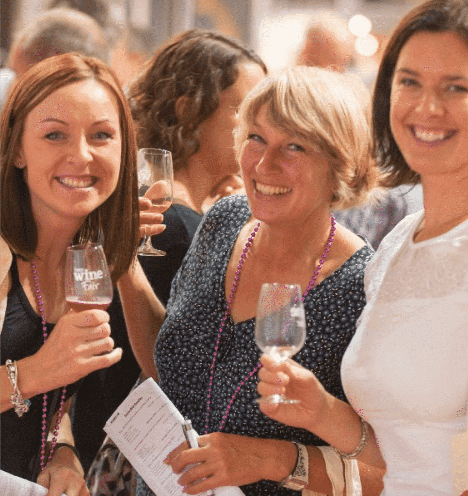 Three women enjoying a wine fair.